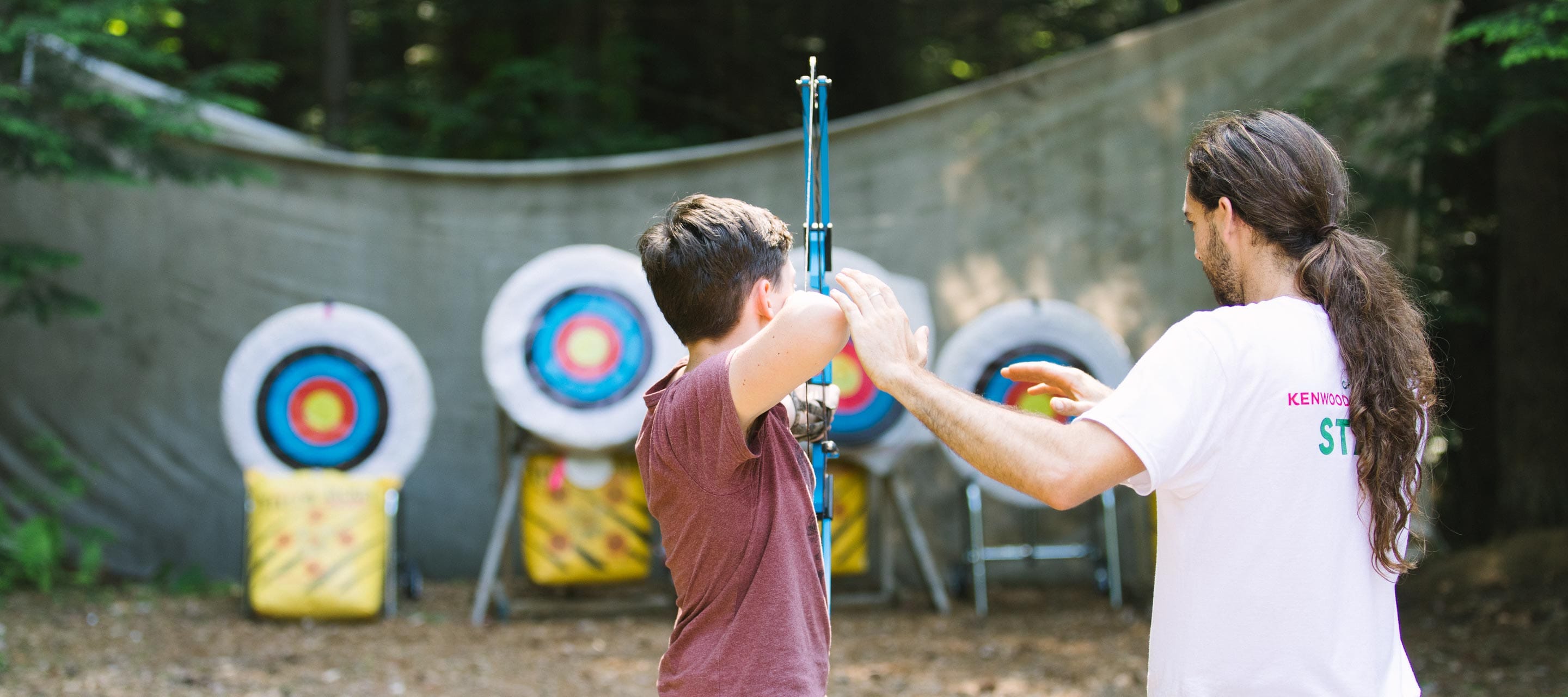 Staff teaching camper archery