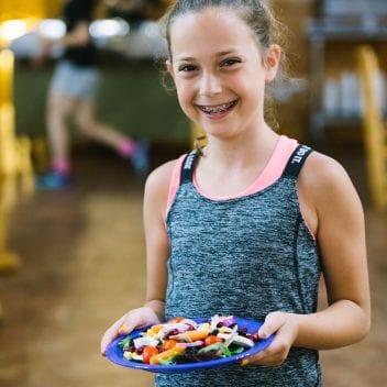 Young female camper holding a plate with veggies