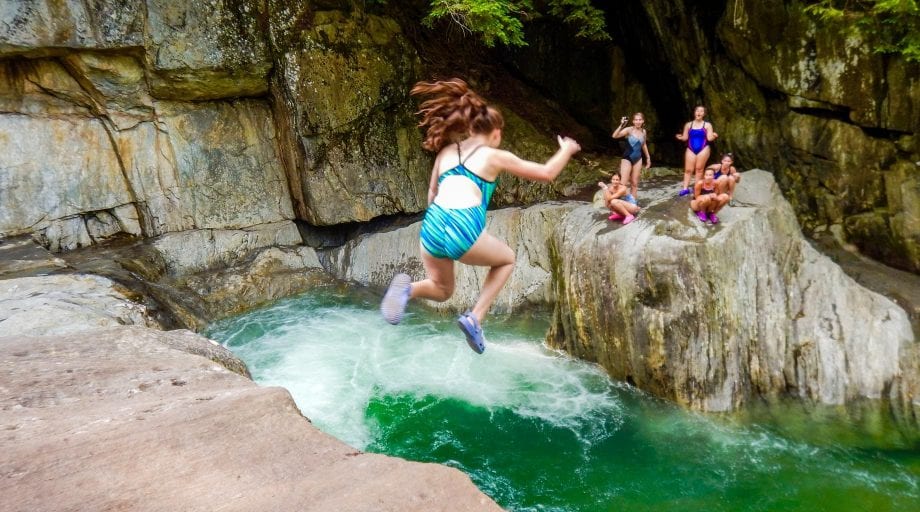 Girl jumping into waterhole during an outdoor adventure trip