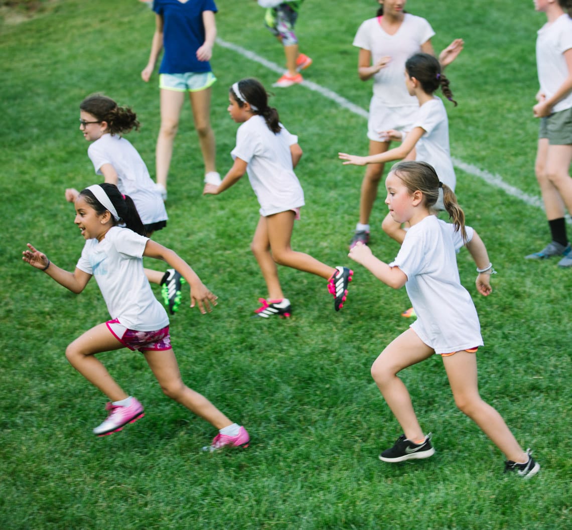 Girls running on field wearing white