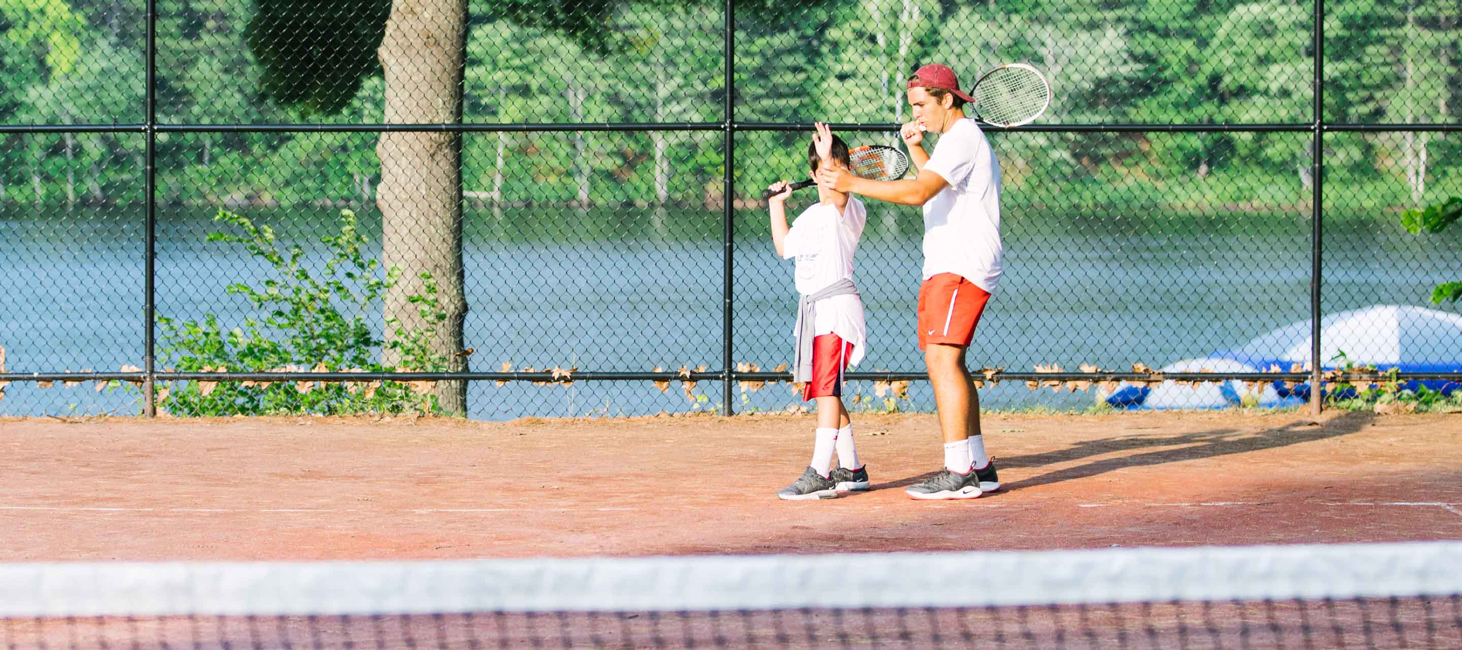 Tennis specialist teaching camper how to serve