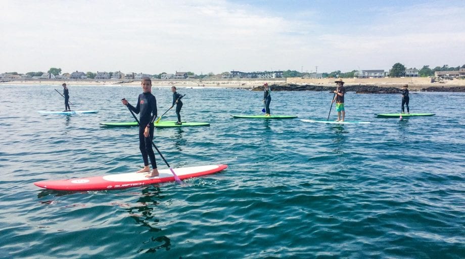 Campers on stand up paddleboards on ocean