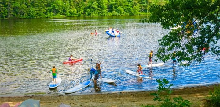Campers on stand up paddle boards and kayaks