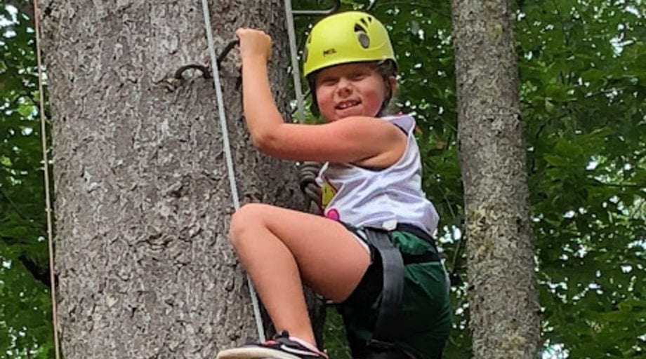 Girl on high ropes course climbing a tree