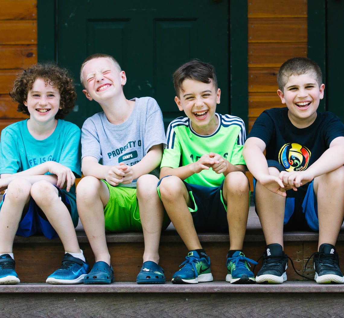 Four happy boys sitting on bunk steps