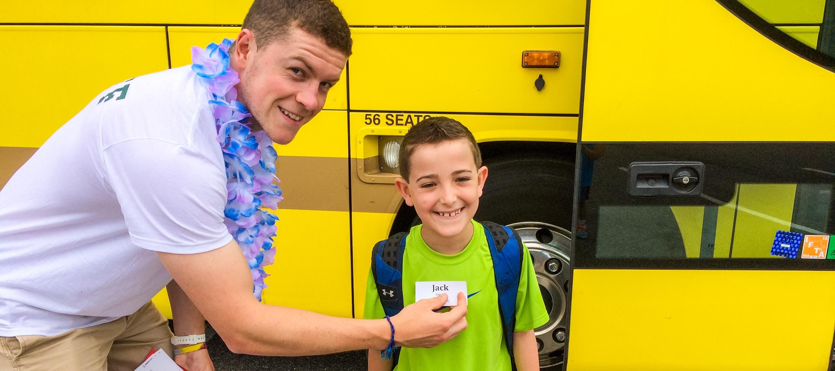 Putting name tag on camper by school bus