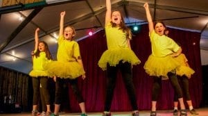 Campers in yellow and black dancing on stage