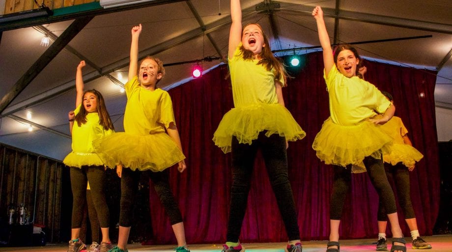 Campers in yellow and black dancing on stage