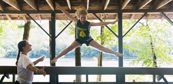 Girl jumping off balance beam during gymnastics