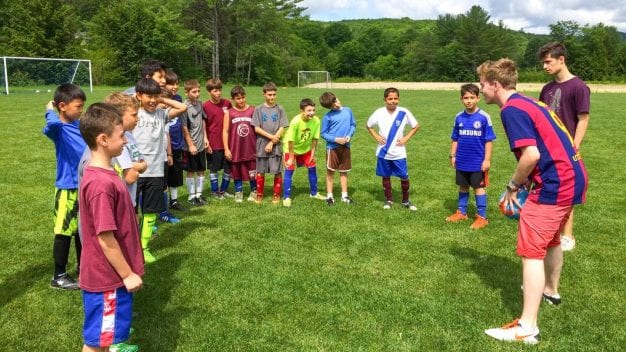 Soccer instructor with campers in a circle