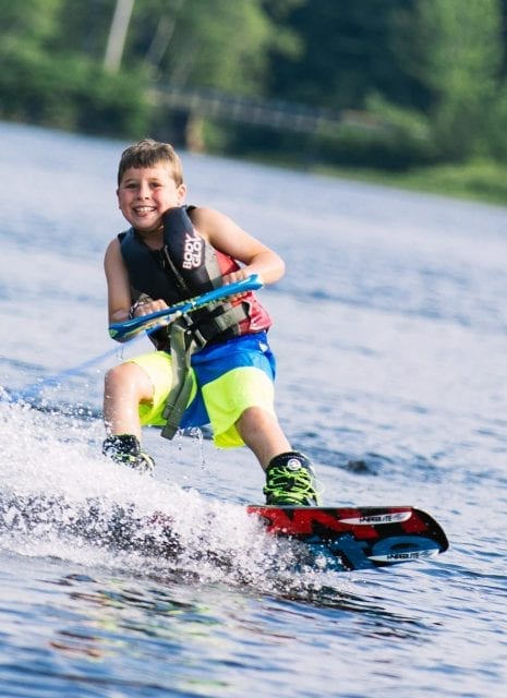 Boy wakeboarding on lake