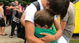 Big brother hugging camper