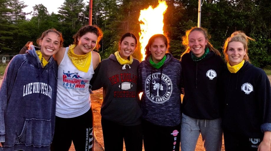 Teens smiling by fire with bandanas on